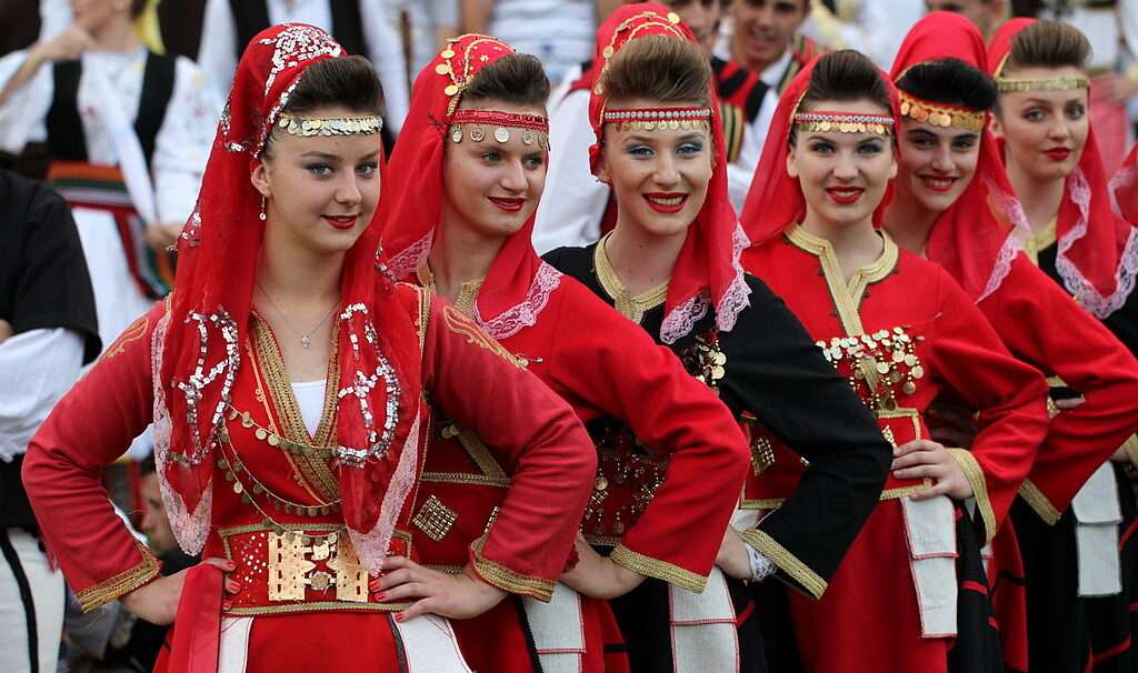 Bunte Szene eines traditionellen albanischen Festivals mit tanzenden Menschen und traditioneller Musik.