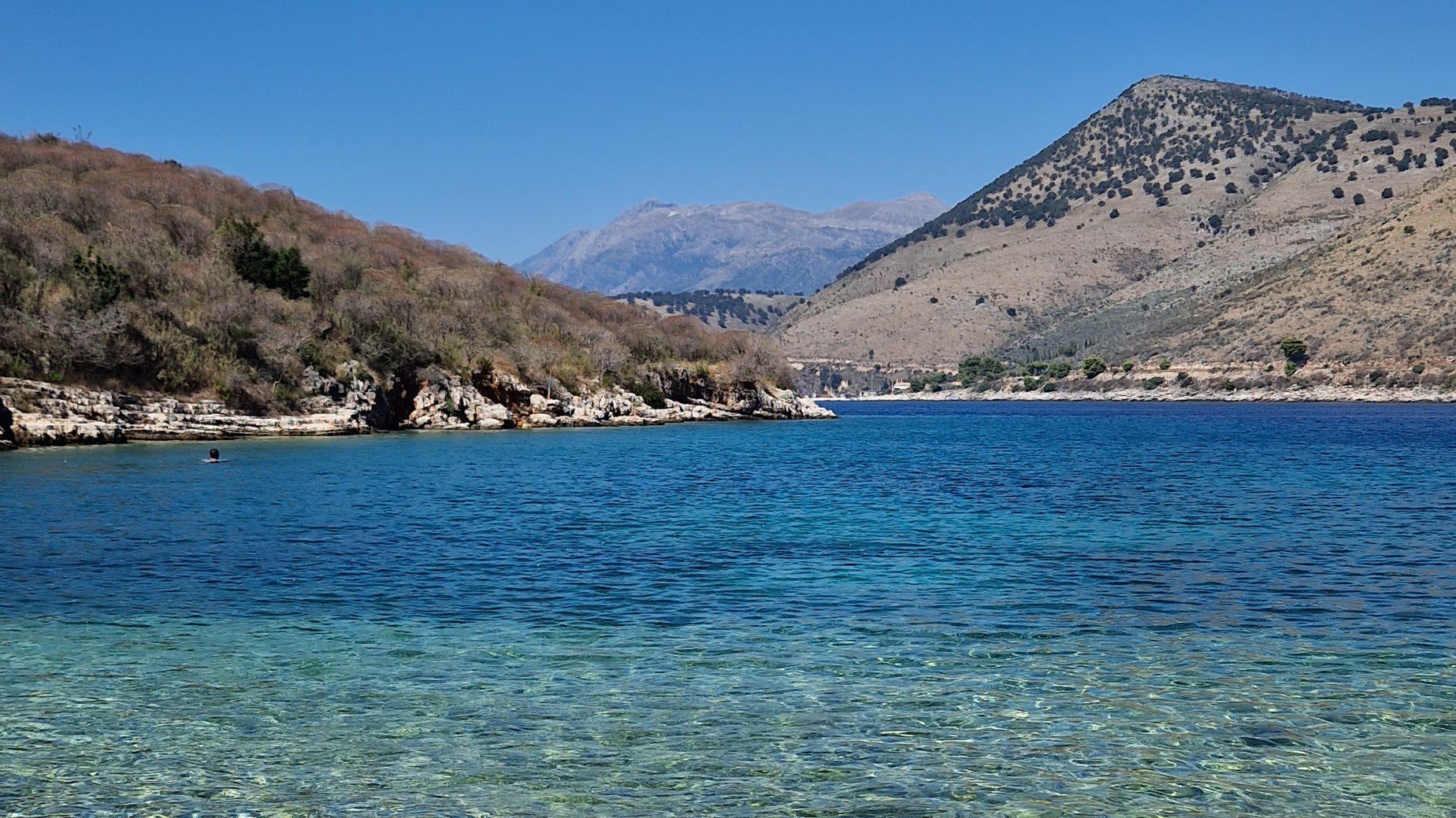 Entdecken Sie einen versteckten Schatz: Ein kristallklarer Strand mit hügeliger Landschaft nur wenige Minuten von Qeparo entfernt.
