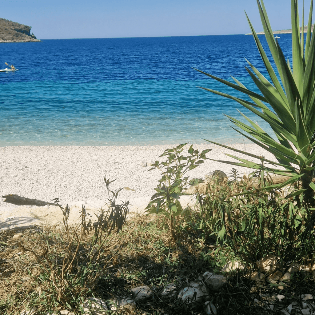 Eine idyllische Oase in Reichweite: Eine friedliche Bucht nur wenige Minuten von Qeparo entfernt, mit Blick auf die Burg von Porto Palermo und das Restaurant Nemo.